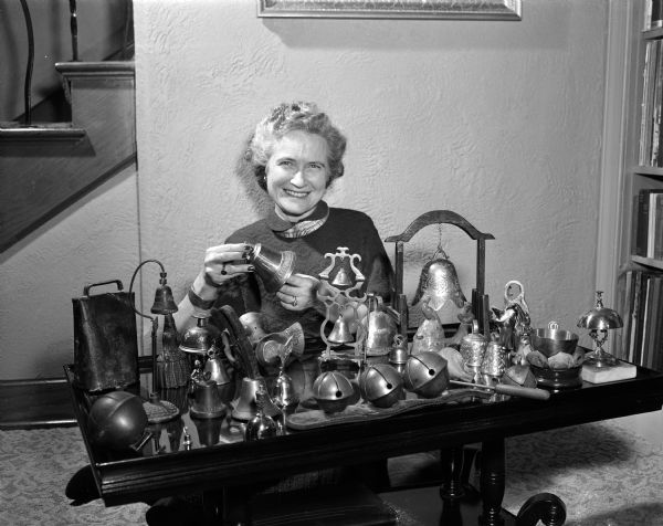 Mrs. Ernest B. Steen of 2205 Lakeland Avenue, wife of new pastor at Trinity Lutheran Church, demonstrates a Christmas custom by displaying her bell collection.