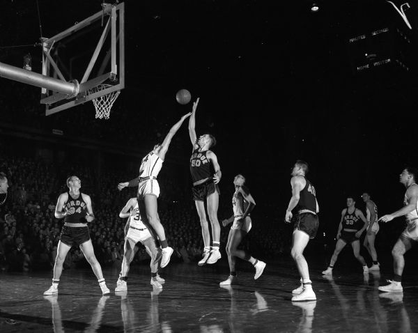 University of Wisconsin vs. Purdue Basketball Game Wisconsin's Tony Stracka and Purdue's Ted Dunn jumping two and a half feet up off the floor while battling for a rebound during a game against Purdue. A referee and seven other players are looking on.