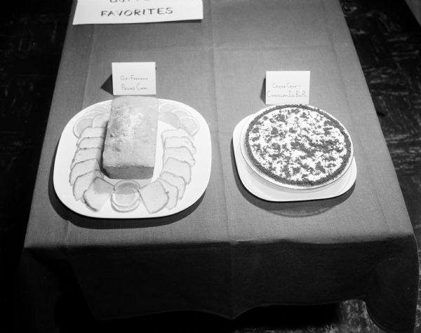 Two examples of foods made with butter are on display during Farm and Home Week at the University of Wisconsin School of Home Economics. At the left is an old-fashioned pound cake and on the right is a chocolate ice box pie with a crumb crust.