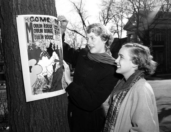 Elizabeth Burton (left), Kappa Kappa Gamma, and Mary Ann Strong, Kappa Alpha Theta, put up a poster for "Moulin Rouge," the University of Wisconsin's Panhellenic dance.