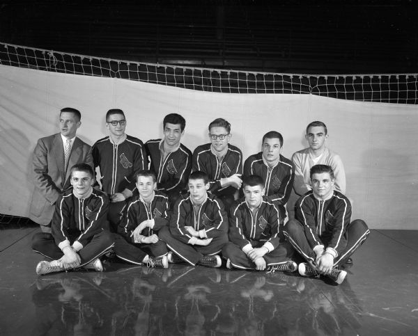 Group portrait of the coach, manager, and nine members of the Milwaukee South High School wrestling team at the University of Wisconsin-Madison Field House. The team had just won its fifth straight WIAA state wrestling meet.