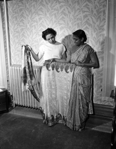 Anna Chandapillal (right) demonstrates how to pleat the front of a sari modeled by Lenore Gourdin (left).
