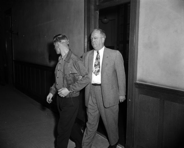 U.S. Marshal Ray Schoonover leaves a hearing in Federal Court with Paul S. Hauser (left), accused of a bank hold-up in Barron County.