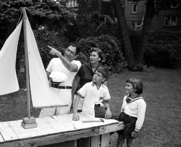 Dr. and Mrs. George (Elizabeth) Maloof of 636 East Gorham Street and their children George ("Mickey"), 8, and Patty, 7, look at the sailboat made by Dr. Maloof. They enjoy sailing on Lake Mendota.