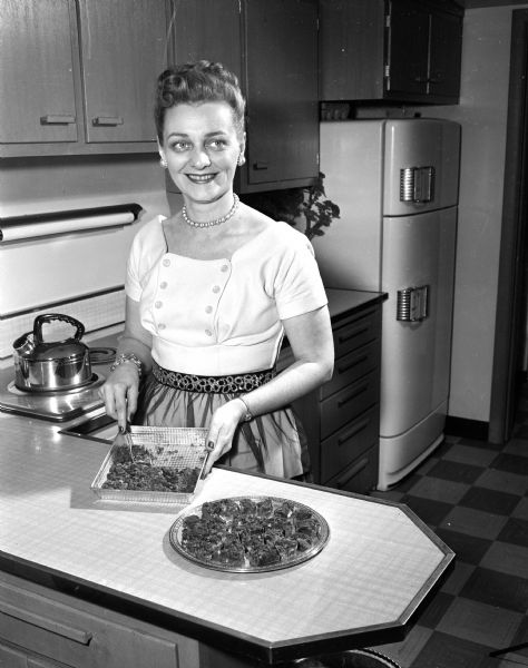 Fern Thompson stands in her kitchen while preparing food for a University of Wisconsin football pregame party. She will be serving a chicken casserole, rolls, a jello salad, and fudge.