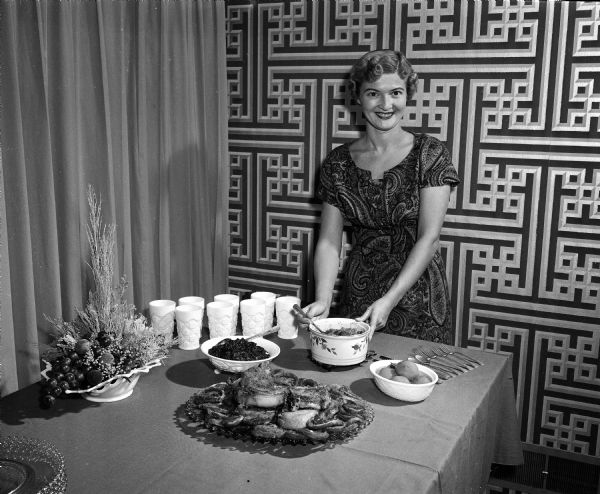 Marilyn Sachtjen standing in her dining room while preparing the serving table for a University of Wisconsin football pregame party. She will be serving stuffed pork chops and baked beans.