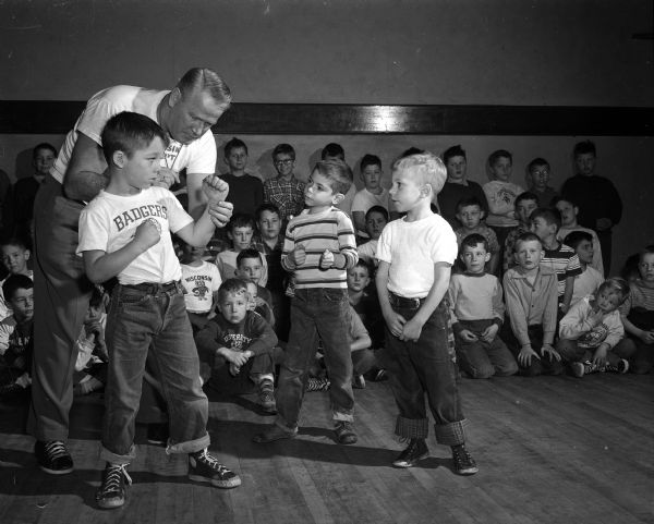 Vern Woodward, University of Wisconsin assistant boxing coach, helps young students during a "Little Boxers" class at the Eagles Club, 23 West Doty Street. Woodward helps Ronnie Eservig take the proper boxing stance while Ricky Raznikov, center, and Tommy Wagner, right, watch.