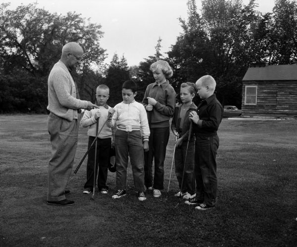 Golf Lessons for Children at Glenway Golf Course "Dutch Vetter (left), Glenway clubhouse supervisor, gives some courtesy 'dos and don'ts' to a group of young golfers. They are, left to right, Michael Madigan, Charles Iane, John Kavanaugh, Sandra Wellenkotter, Vickie Gessler, Steve Herreld. The three boys and two girls are holding golf clubs.