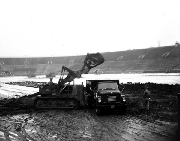 Excavating machines start lowering historic gridiron for a "facelift" of Camp Randall's stadium.