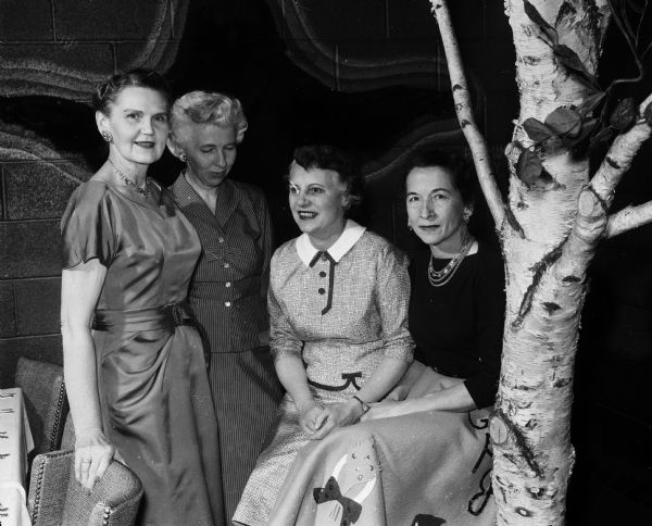 Group portrait of the cast for a skit called "The Women," entertainment for the Badger Bonspiel banquet. The women include, left to right: Emily Ahearn, Dorothy Ela, Agnes Gurney, and Gene Johnson.