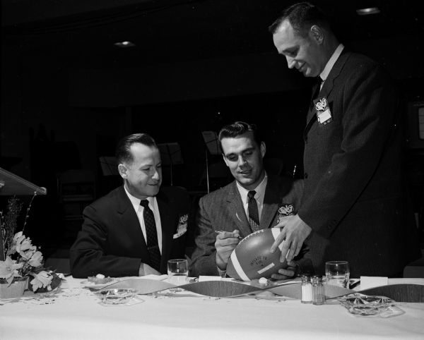 Guest speaker at a father-son banquet at Immanuel Lutheran Church is Gary Knafele (center) of the Green Bay Packers football team. He is autographing a football, with Ray Bohl, left, and Melvin Reimann, nearby.