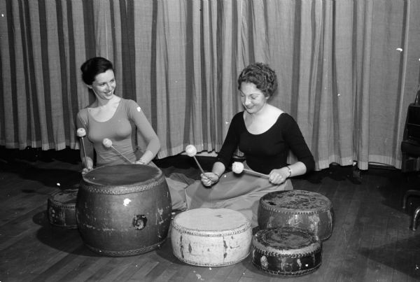 Almost 200 girls from 20 Wisconsin high schools took part in a strenuous day of recreation planned by the Women's Physical Education Club at Lathrop Hall at the University of Wisconsin. Two members of the Women's Physical Education Club beat out a rhythm on the drums for creative dancing activities. The drummers are Nancy Barden and Diane Dobbins.