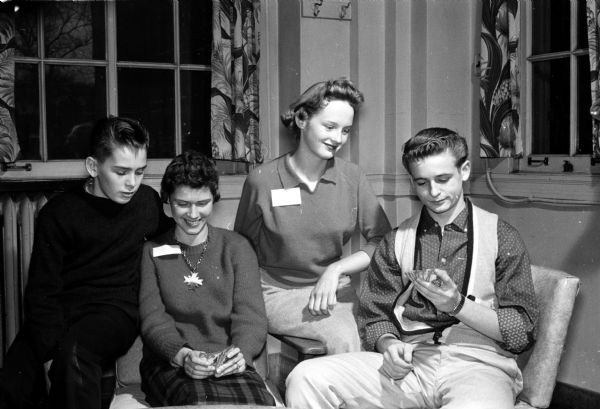 YW Teen-Canteen Activities at the Teen-Canteen at the YWCA, 122 State Street, are sponsored by the Junior High Y-Teen clubs in Madison. A foursome involved in a card game are, left to right: John Peterson, Mary Jo Handel, Mary McDonough, and Devon Broadbent.