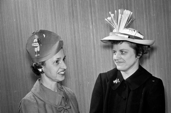 Original colorful hats of all types and designs appeared at the spring "Mad Hat" luncheon at the Blackhawk Country Club. Irene Marsh and Ann Rundell wore hats to represent their husbands' occupations. The wife of one of Wisconsin's coaches, Irene Marsh, wore a "football" cap of overseas type trimmed with souvenirs of the fall season. Ann Rundell, the wife of a dentist, chose a neutral straw hat with a trim of false teeth, toothpaste and brush, cotton pads and other dental accessories.