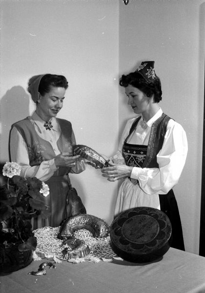 An authentic Scandinavian smorgasbord will be the key attraction at Madison's first Folk Festival and Fair sponsored and held at the YWCA, 122 State Street. Winona Foster, left, and Helen Bruce model costumes to be worn at the Scandinavian smorgasbord. The fair program will include a puppet show, folk arts, exhibits and teas.
