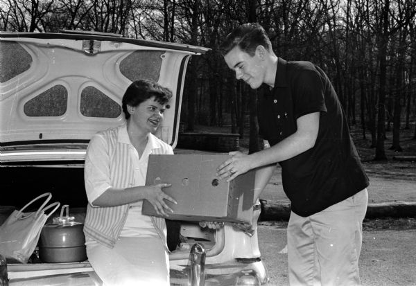 Attending a picnic for teenagers at a Madison park are Judy Fiege, left,and Tom Kretschman. Judy is handing Tom a box of picnic supplies.