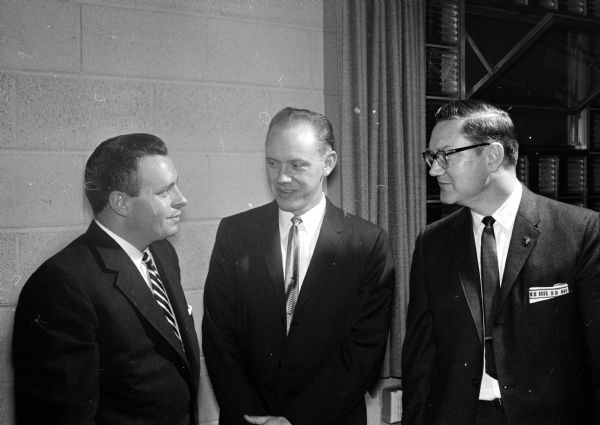 Three members of the Madison chapter of the American Institute of Banking are shown at the annual meeting. They include, standing left to right, John Swanton, Willard Olson, and Phil Rindy.