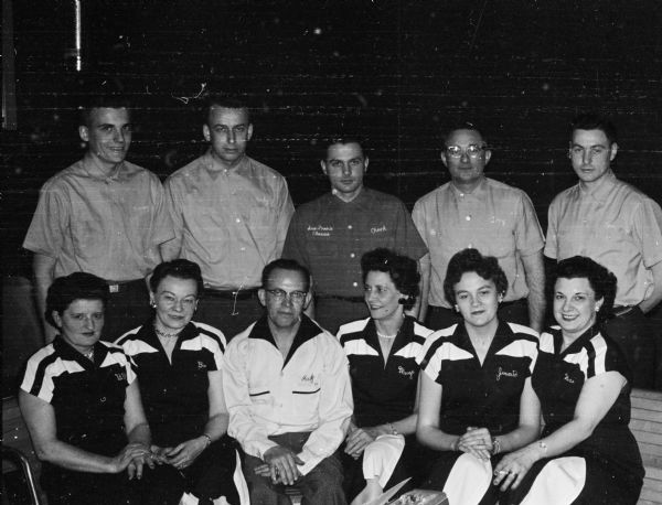 Rudy Crandall sits amid his two championship bowling teams sponsored by his bar and restaurant. In front are members of the championship Playdium Metropolitan Ladies League team. Left to right are: Billie Crandall, Bea Nall, Crandall, Marge Christy, Jennie Crego, and Rose Edmunds. In back are members of the Bowl-A-Vard Major League championship team. Left to right are: Ron Brischke, Kirby Battist, Tony Wagner, and Tom Weigen.
