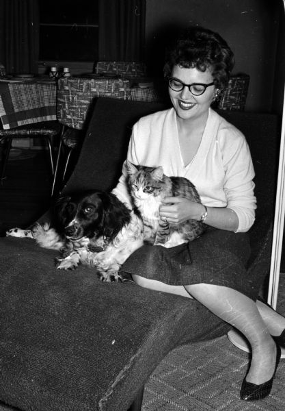 Mrs. Mary Myre is sitting next to her Cocker Spaniel dog while holding a calico cat she rescued from a tree.