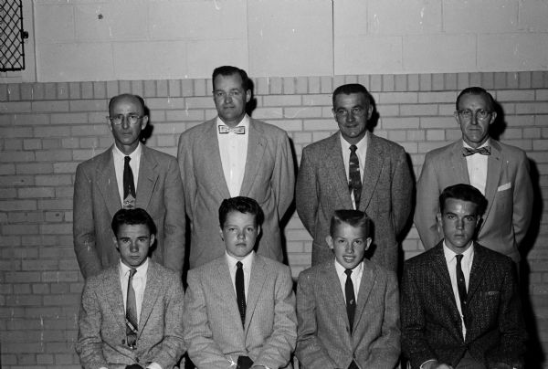 Group portrait of four father and son pairs. In the front row are Ed Francis, co-captain in football; Tom Hilsenhoff, softball co-captain; Tom McKay, track co-captain; David Johnson, captain in football, basketball, and track, and co-captain in softball. In the back row, standing behind their sons, are the fathers, N E. Francis, Robert Hilsenhoff, Norman McKay, and Oscar Johnson.