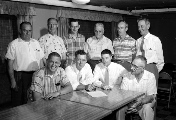 Group portrait of the members of a joint committee from the Madison Shrine Club and Knights of Columbus. The group met to plan the upcoming annual Shrine-KC benefit show and softball game. Members are, left to right, seated:  Steve Slattery, Lyle Andrews, Philip Croak, and Herbert Tetzlaff. Standing: Joseph Tesserand, Herbert Smith, Jonas Rowley, Joseph Porter, James Lynch, and Walter Hendrickson.