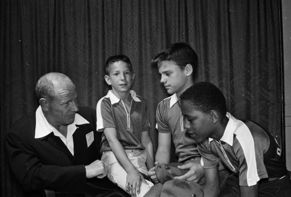Bill Veeck (left), president of the Chicago White Sox, chats with three managers of Madison boys baseball teams before speaking at the downtown Optimist Club. The boys are (left to right): Greg DuBois, Paul Zmudzinski, and Pheron Doss.