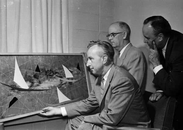 Unofficial Ambassadors, Inc., a non-profit corporation devoted to further international understanding through cultural exchange, will sponsor a tour of Mexican art in Wisconsin. Officials look over one of a group of paintings to be included in the tour. Shown (left to right) are former Governor Vernon W. Thomson, committee member; the Rev. Alfred W. Swan, minister of the First Congregational Church, committee member; and John E. Merkel, Jr., executive director of the group.