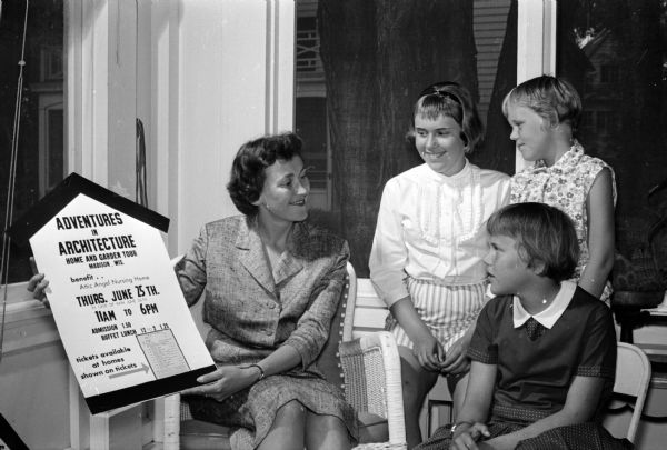 Alicia, Claire, and Tecia Findorff, (right) young daughters of Mr. and Mrs. John R. Findorff, admire a poster that their mother (left) made and distributed to promote the Attic Angels house tour "Adventures in Architecture."