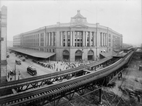 Elevated view of the South Station terminal with elevated track in the foreground, Boston, Massachusetts. Streetcars and pedestrians can be seen on the street below. The South Station was created in the late 1890s when it was no longer efficient for each of the five railway companies that serviced Boston to have their own depot.