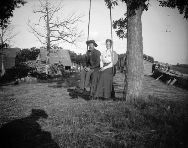 Man and Woman on Swing A man and woman, possibly Mr. and Mrs. Andrew and Clara Larson (?) of Hoffman Creek sit on a tree swing. The shadow of the photographer is visible on the grass.