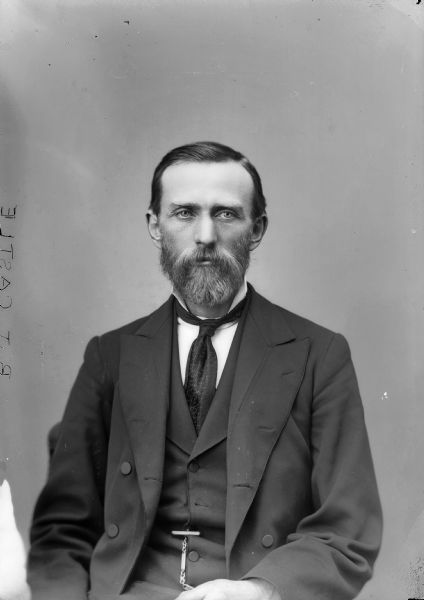Portrait of B.J. Castle A studio portrait of a well-dressed, bearded man, identified as B.J. Castle. He is wearing a suit jacket, vest with watch fob, necktie, and trousers.