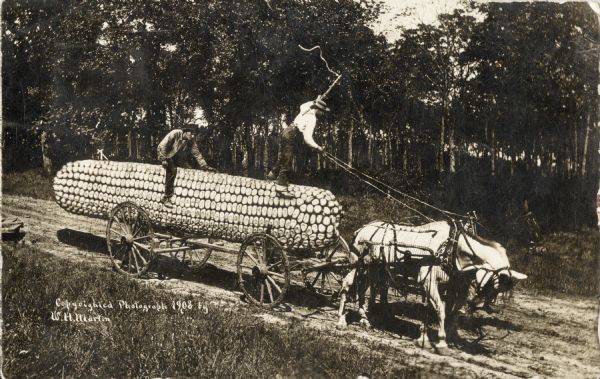 Photomontage of two men riding a giant ear of corn resting on a large, flatbed horse-drawn cart. The driver is standing on the corn, preparing to whip the downtrodden horses onward, while the second man is sitting on the corn as though it were a saddle.