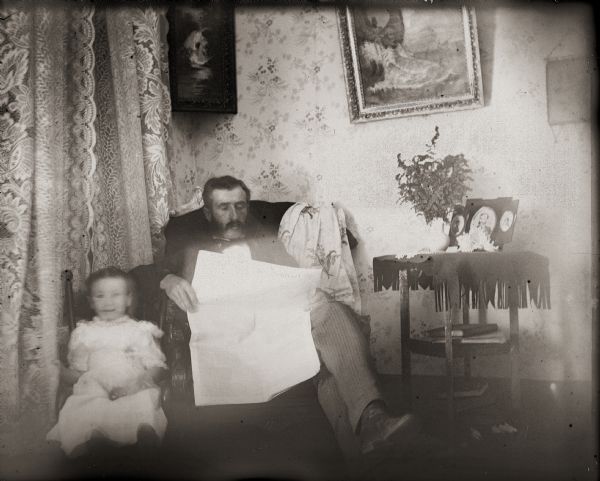 Dr. Edward A. Bass reading the newspaper while seated next to his daughter, Everetta.
