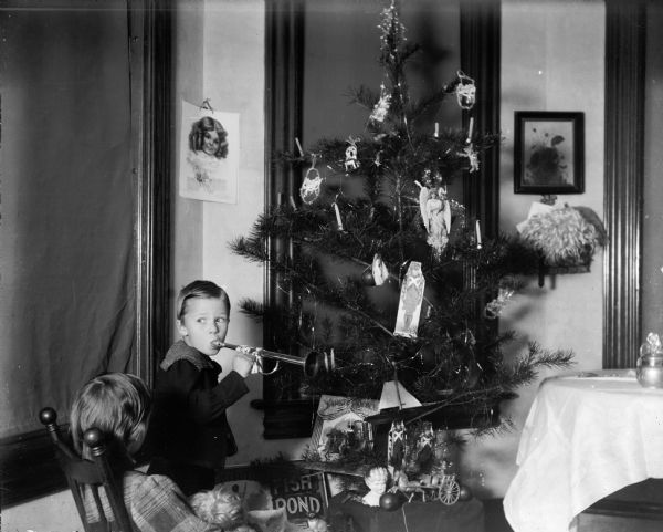 Cary and Everetta Bass with their Christmas tree. Cary holds a toy horn; Everetta holds a doll.