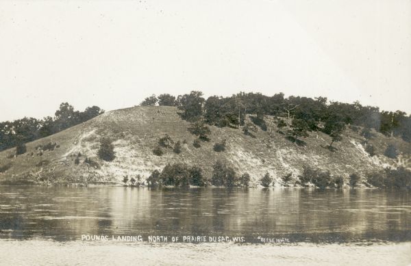 A view of the west bank of the Wisconsin River at Pounds Landing. This bluff is at the western end of the power dam which was constructed 1911-1914. Caption reads: "Pounds Landing North of Prairie du Sac, Wis."