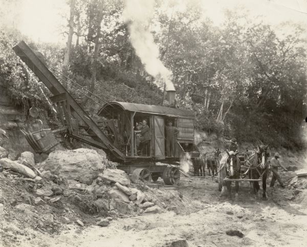 Road construction crew of the Nelson Weber Construction Company and steam shovel. This construction was photographed for the Wisconsin Good Roads Association.