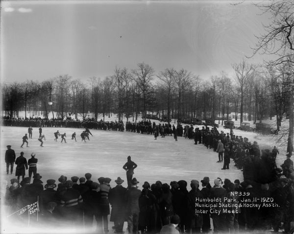 Crowd in Humboldt Park watching an ice skating race. Caption on glass plate reads: "Municipal Skating and Hockey Association, Inter City Meet".