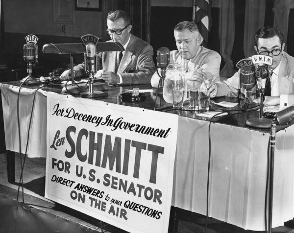 Len Schmitt, former Progressive Party legislator from Merrill, led the Republican opposition to Senator Joseph R. McCarthy's bid for re-election. Schmitt attempted to call attention to his "Decency in Government" campaign with a 25-hour radio talkathon. He is seated here with Mike Griffin, a radio announcer and his campaign manager; a local radio announcer is to his left. Schmitt anticipated there would be no Senate primary race on the Democratic ticket which would have allowed Democrats to cross over and vote for him. Instead there was a tight race between Henry Reuss and Thomas Fairchild. Senator McCarthy handily defeated Schmitt in the primary.