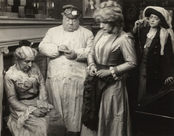 Scene still from the Vitagraph production <i>Treasure Trove.</i> Left to right are Mary Maurice, John Bunny, Julia Swayne Gordon, and Helen Gardner. John Bunny is dressed for an automobile ride. He wears a leather hat, goggles, and a duster.