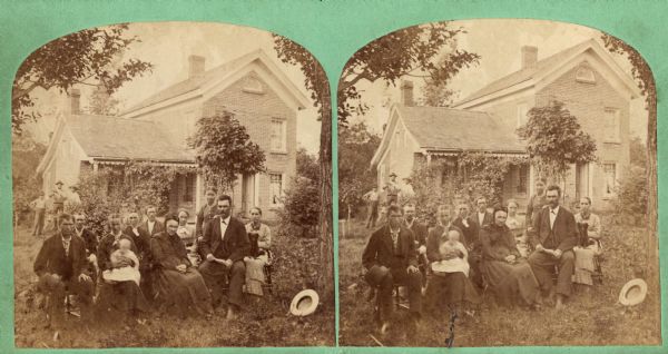 Bechtel family seated in yard with croquet mallets in front of them with brick house that has soldier coursing at windows and fan window at third story. Daniel Bechtel is seated next to his widowed mother Catharine Bechtel.  Her husband John Bechtel died Feb. 5, 1876.