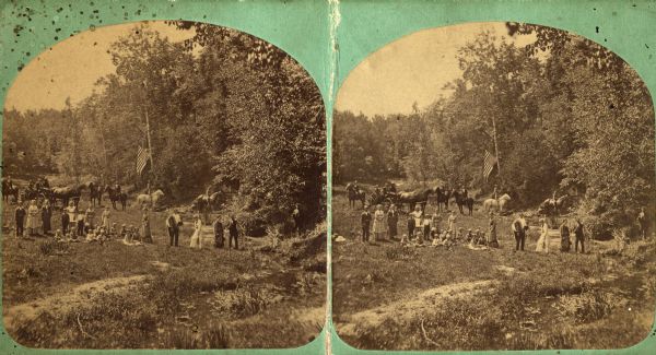 Boy on Horse Amid Picnickers Group in field on picnic with flag, man on horse and people in carriages. A boy is standing on horse in the background. Photograph for "Mr. Miller."