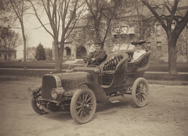 Alice M. Tilleson, member of the Menomonie High School class of 1905, depicted as a prominent socialite. Pictured being escorted in the back of an automobile. Part of a yearbook created by classmate Albert Hansen, based on a class prophecy theme.