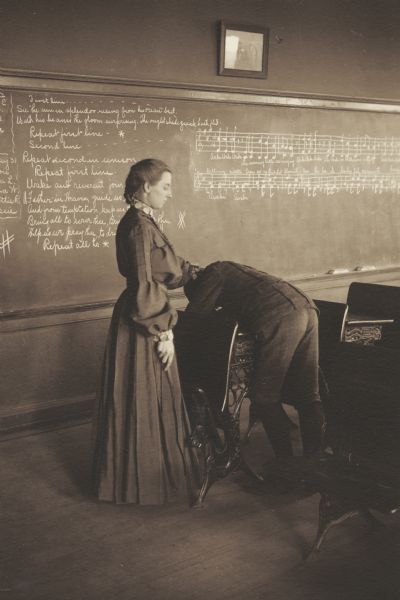 Magdalina Sara Jungck, member of the Menomonie High School class of 1905, depicted as a school teacher, lashing a boy student over a desk. Part of a yearbook created by classmate Albert Hansen, based on a class prophecy theme.
