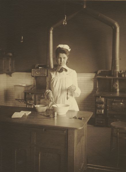 Bertha L. Retelsdorf, member of the Menomonie High School class of 1905, depicted as a cook . Part of a yearbook created by classmate Albert Hansen, based on a class prophecy theme.