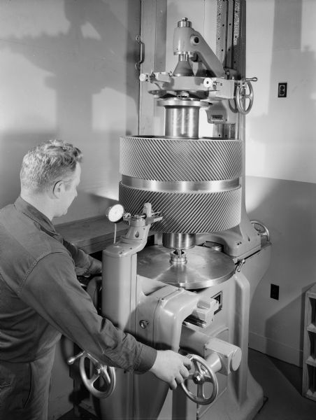 A male employee inspects a H.S. Grigate Gear. This gear, a marine propulsion drive, was later used by the United States Navy.