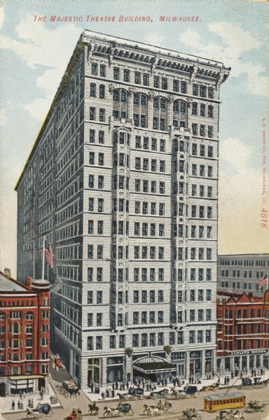 Elevated view of fourteen-story theatre building, with two red buildings on either side of it. On the street are people, horses, carriages, and trolleys. Caption reads: "The Majestic Theatre Building, Milwaukee."