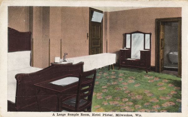 The hotel is on the corner of Wisconsin Avenue and Jefferson Street. The view is of large sample room. Includes a bed, desk and chair, vanity dresser, a long table with a telephone, and a view of the bathroom through the doorway. Caption reads: "A Large Sample Room, Hotel Pfister, Milwaukee, Wis."