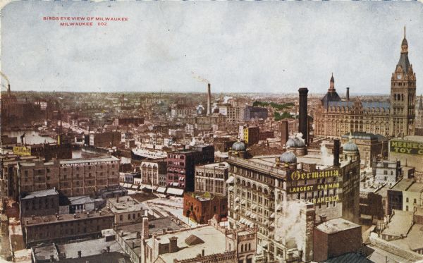 Elevated view of downtown. Part of the Milwaukee River is on the left side. Sign for the Germania building is in the lower right, and city hall is in the background. Caption reads: "Birds Eye View of Milwaukee, Milwaukee."