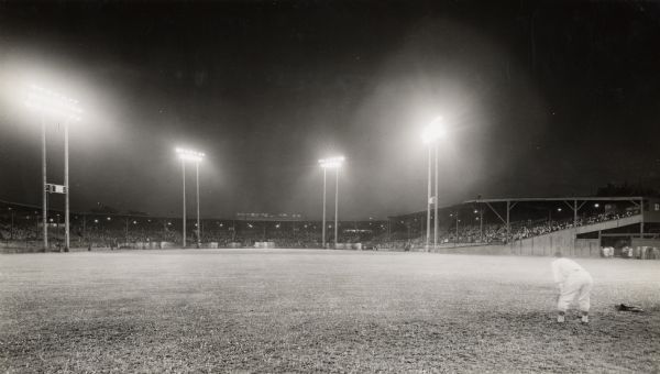 Home of the Milwaukee Brewers Minor League baseball team. Located between W. Chambers and W. Burleigh Streets at N. 7th Street. A player is on the right in the outfield. In the background is the main field, with players running the bases.