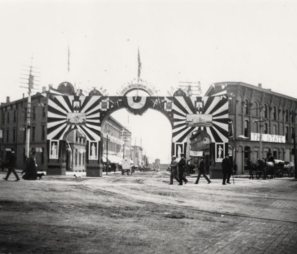 Flags and posters are displayed over King Street for the fifty year celebration. One banner reads: "1848 Wisconsin 1898." Pedestrians are on the streets and sidewalks.